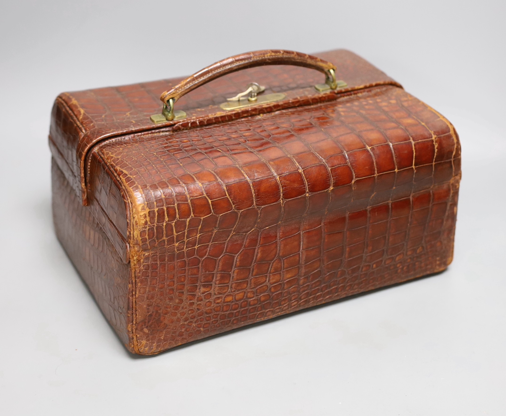 An early 20th century crocodile three tier travelling jewellery bag with key (lock a.f.) - 30cm long